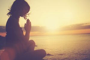 Young woman meditating on the beach